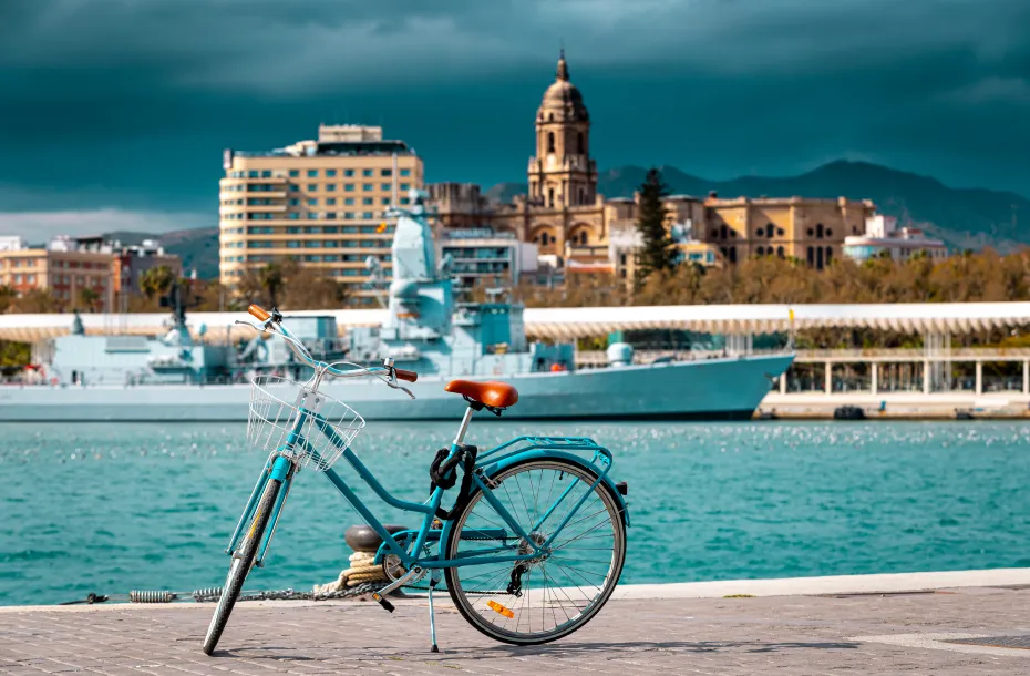 A light blue bicycle at the port of Malaga and the Cathedral of Malaga in the background