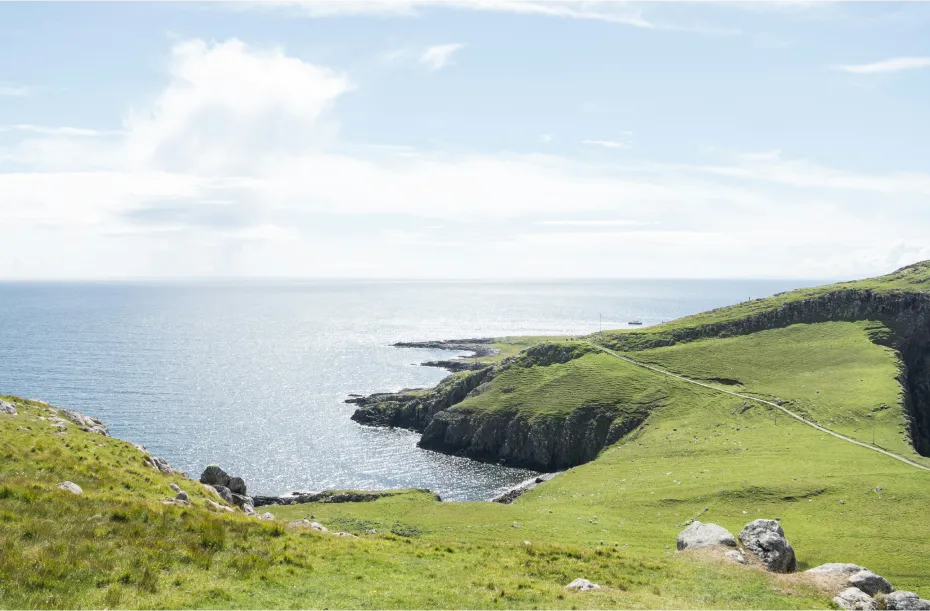 Amazing view of green fields rising above the sea in Scotland