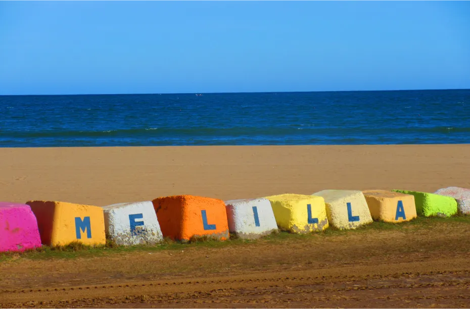 Colorful stones at the beach with an order to write the name of Melilla