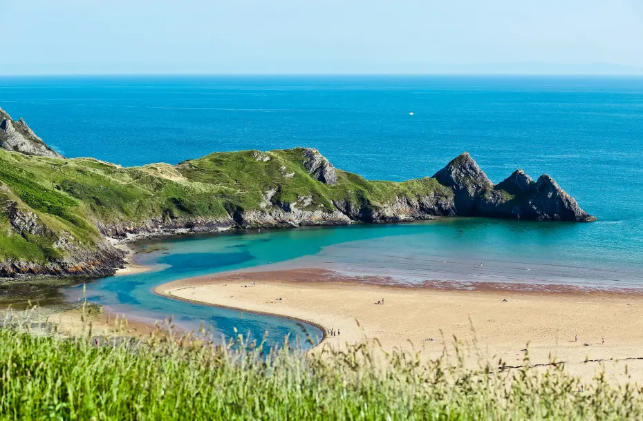 A beautiful beach in Wales with rock formation forming a pier in the ocean